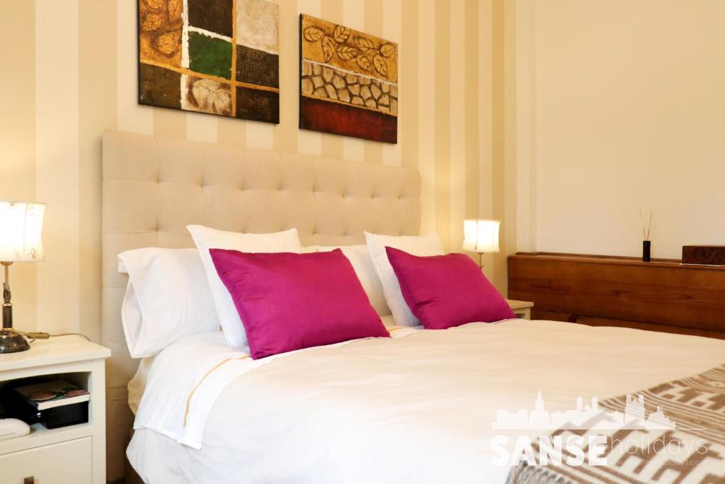 1 dormitorio con 1 cama blanca y 2 almohadas rosas en Apartamento Usan, en San Sebastián