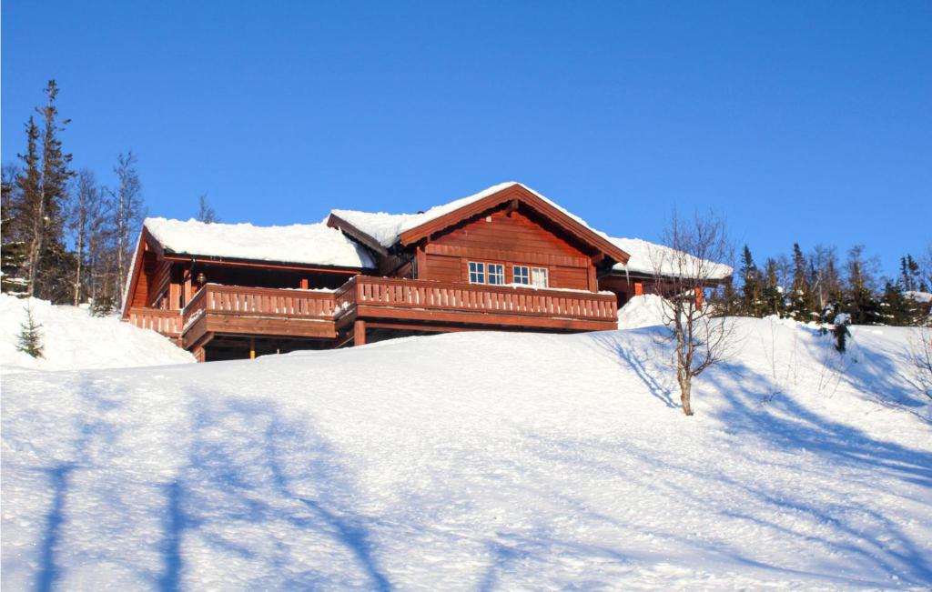 una cabaña de madera con nieve en el suelo frente a ella en Cozy Home In Tuddal With Kitchen en Tuddal