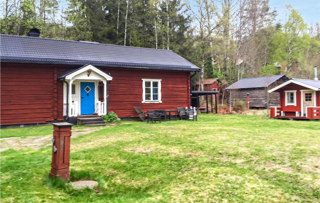 a red cabin with a blue door in a yard at Awesome Home In Lima With Sauna And 2 Bedrooms in Lima