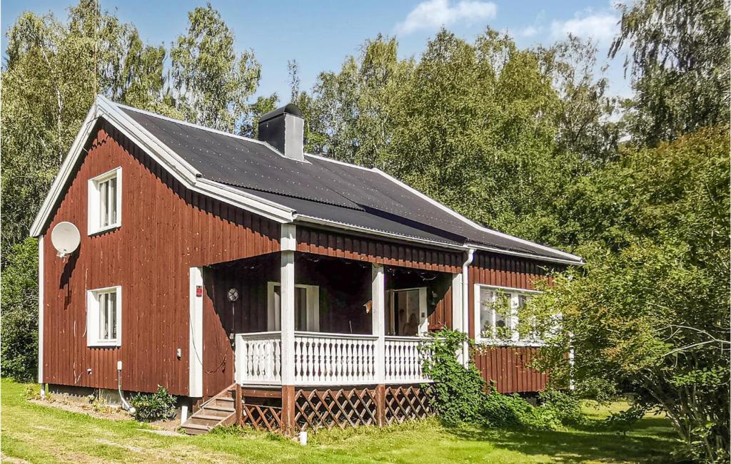 a red barn with a porch on a field at Amazing Home In Karlsviken With Wifi And 4 Bedrooms 