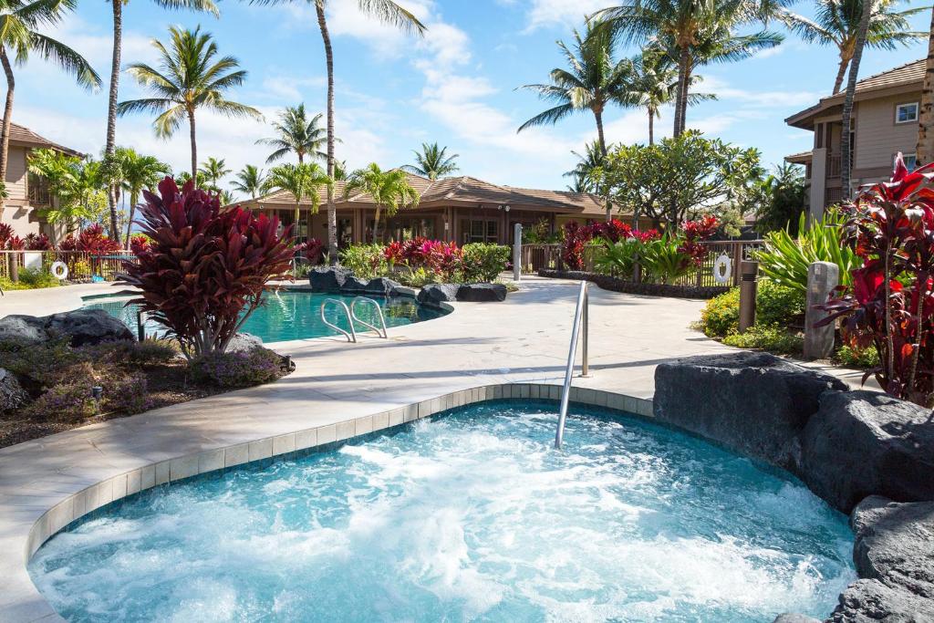 a swimming pool in a yard with palm trees at Newly Updated Condo At Waikoloa Colony Villas in Waikoloa