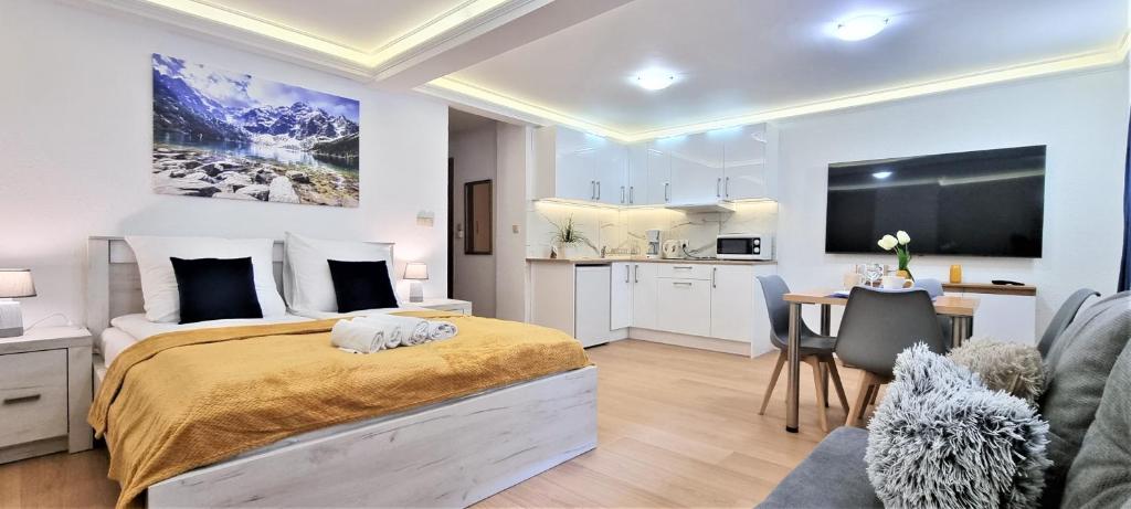 ザコパネにあるVIP Apartamenty Tetmajera Centrumのベッドルーム1室(ベッド1台付)、キッチン、テーブルが備わります。