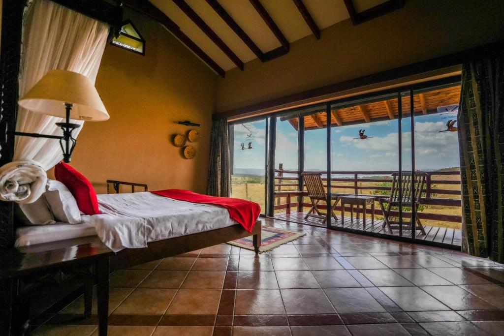 a bedroom with a bed and a view of the ocean at Lake Nakuru Lodge in Nakuru