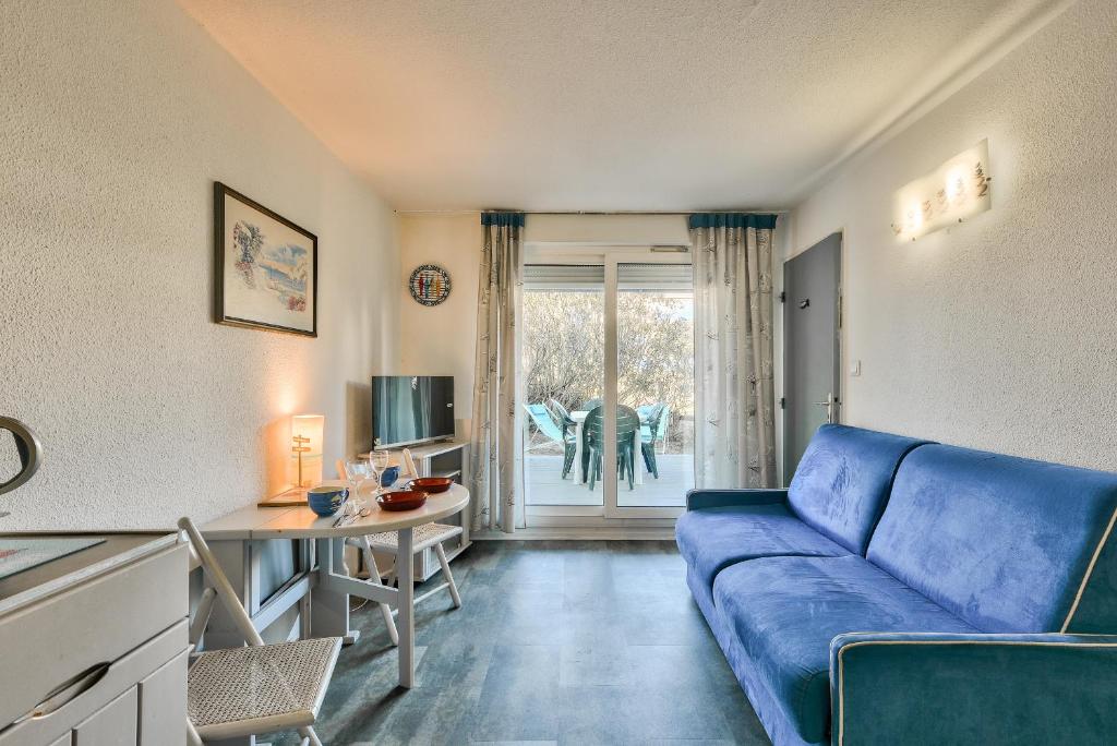 salon z niebieską kanapą i stołem w obiekcie Bord de mer : à 250 m de la plage à Lacanau w mieście Lacanau