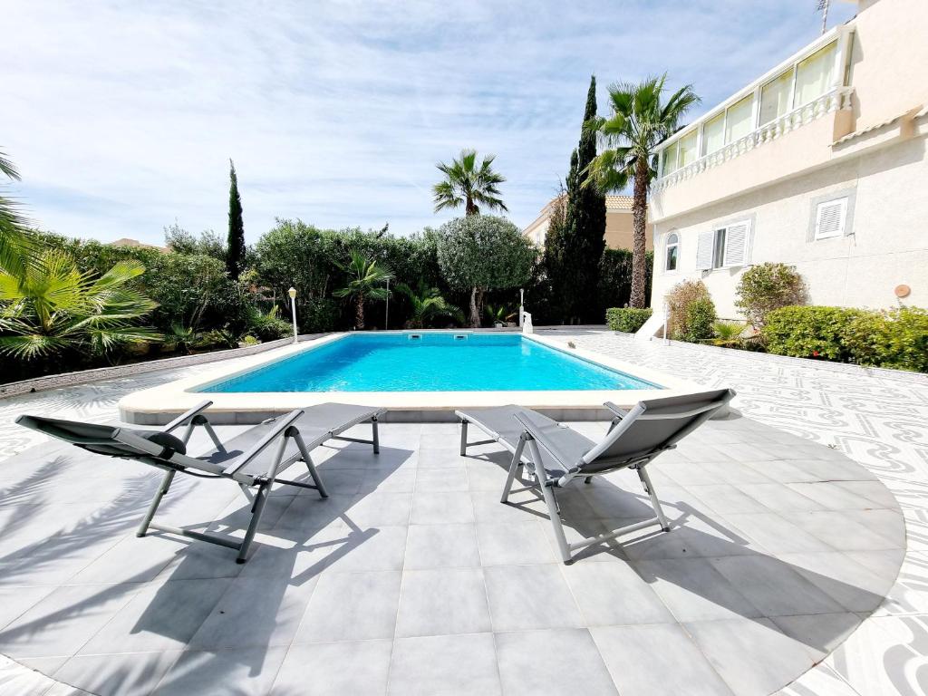 a swimming pool with two chairs next to a house at Detached villa with private pool in La Mata