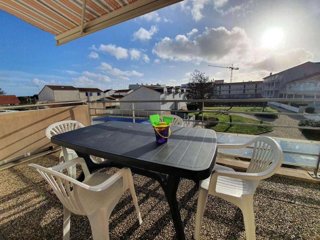 une table noire avec des chaises et une boisson sur un balcon dans l'établissement Appartement 3 pièces avec balcon, piscine collective et parking proche océan à Saint-Hilaire-de-Riez - FR-1-224C-250, à Saint-Hilaire-de-Riez