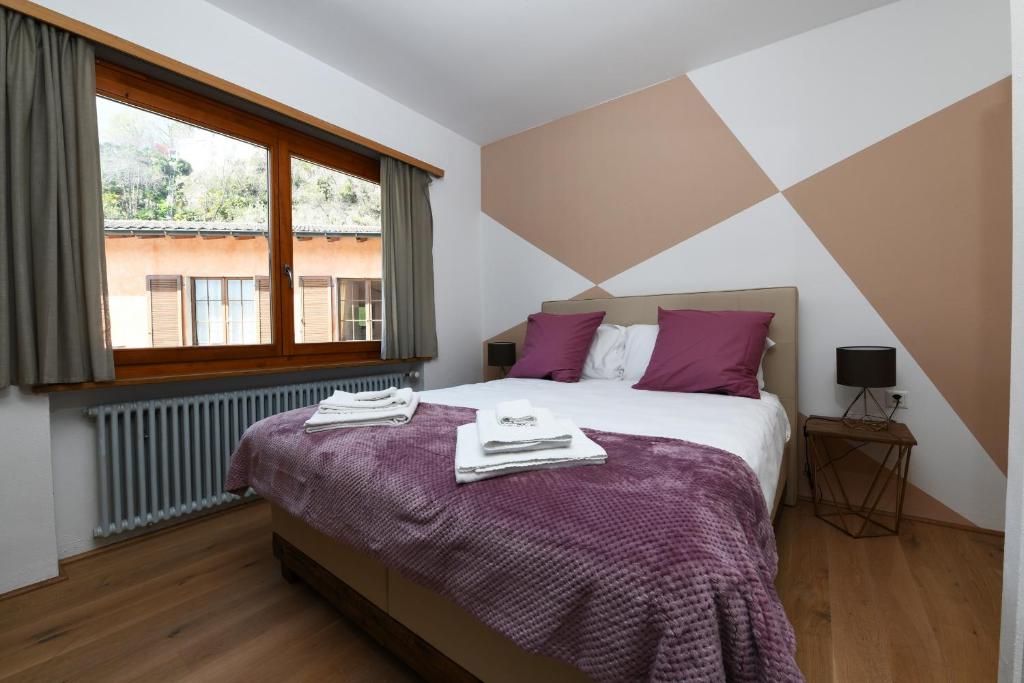 een slaapkamer met een bed met paarse lakens en een raam bij 7rooms Losone in Losone