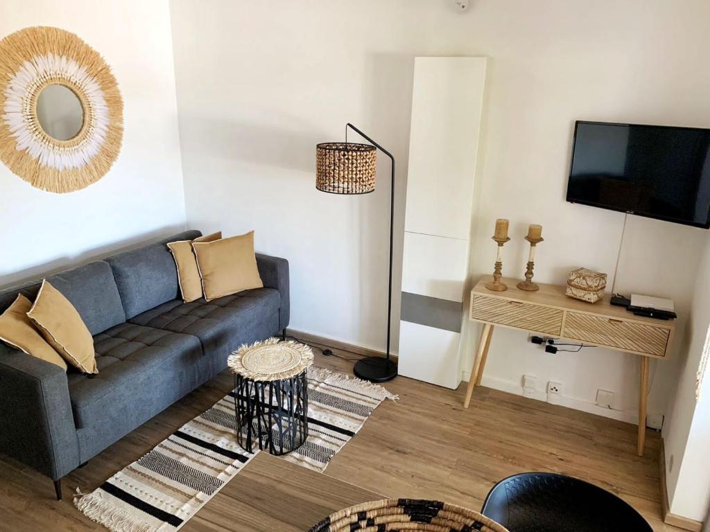 uma sala de estar com um sofá e uma televisão em Kasamia vue mer à St Leu em Saint-Leu
