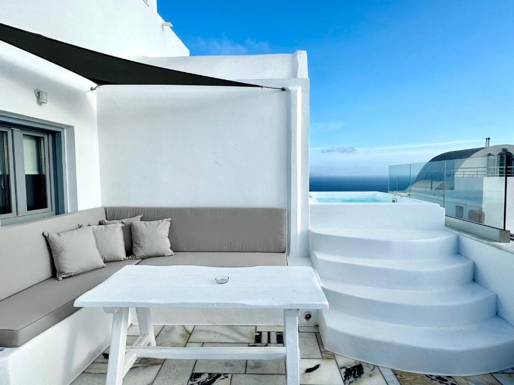 a balcony with a bench and a table on a yacht at Oia Captain's Villa in Oia