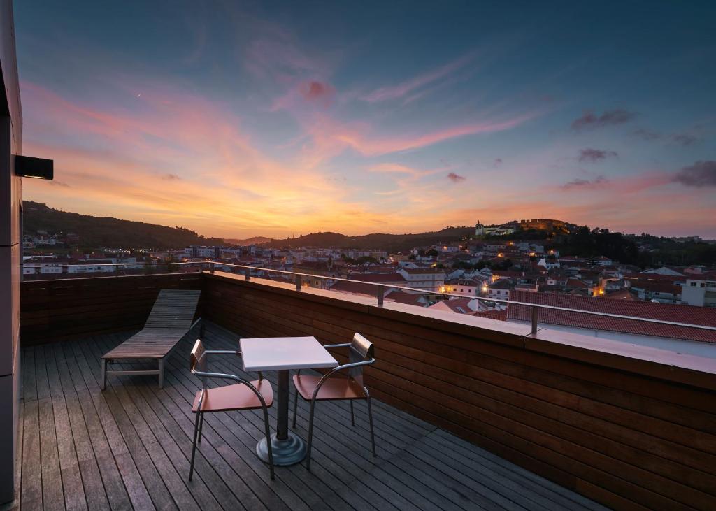 einen Tisch und zwei Stühle auf einem Balkon mit Blick auf den Sonnenuntergang in der Unterkunft Stay Hotel Torres Vedras Centro in Torres Vedras