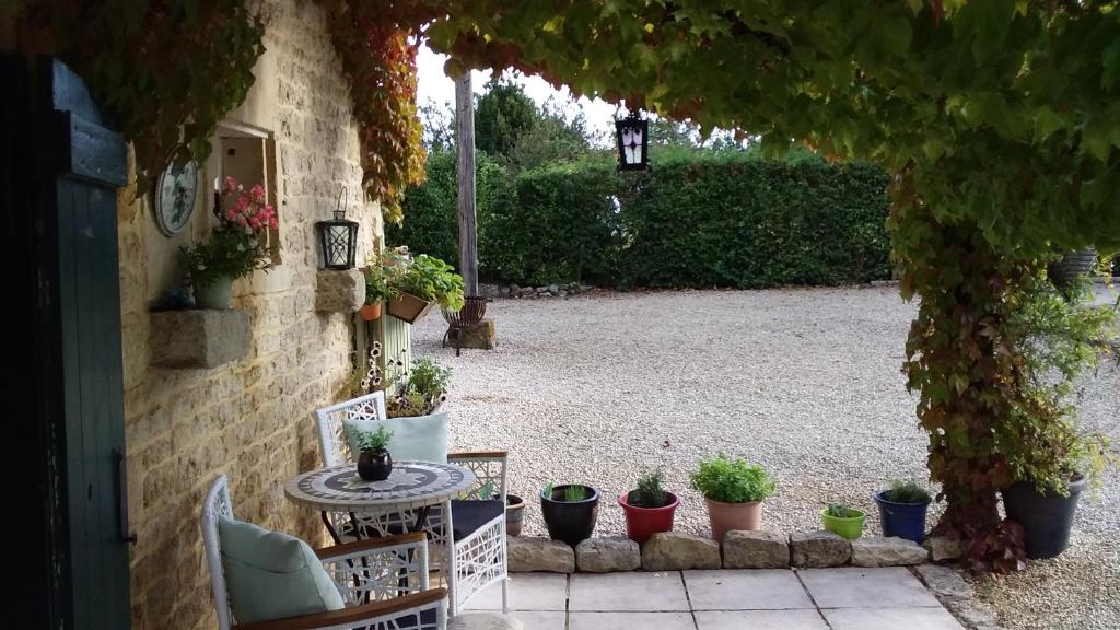 a patio with a table and chairs and potted plants at La Grange de Gournay in  Gournay-Loizé