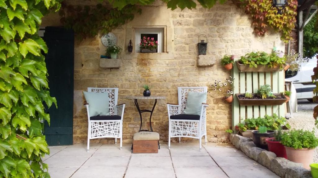 a patio with three chairs and a table with plants at La Grange de Gournay in  Gournay-Loizé