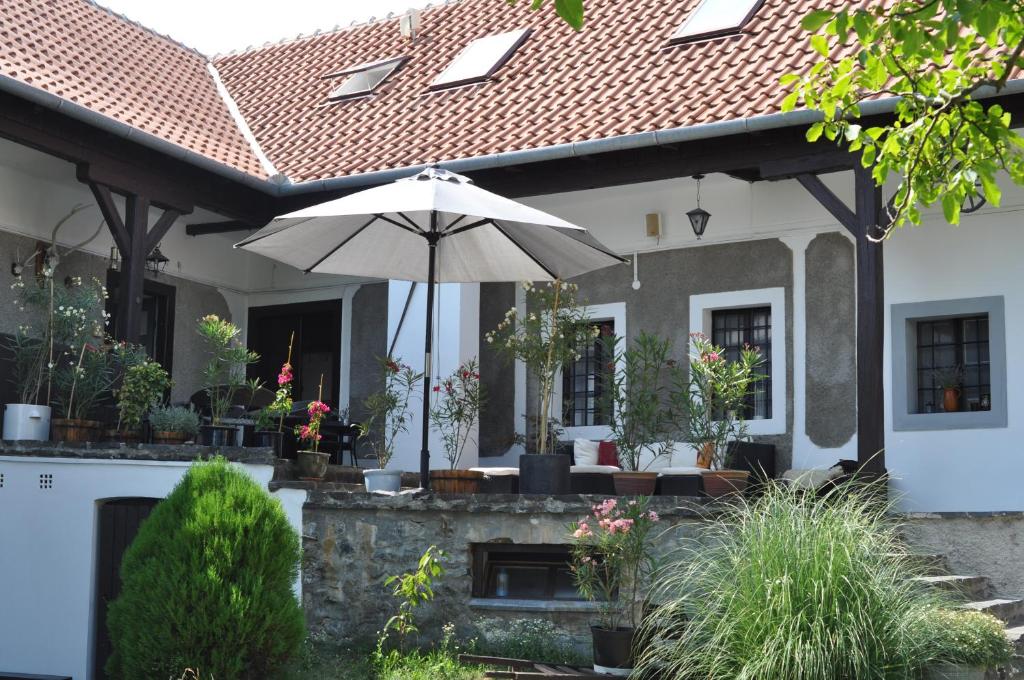 a white house with an umbrella in front of it at Óbester Panzió in Badacsonytomaj