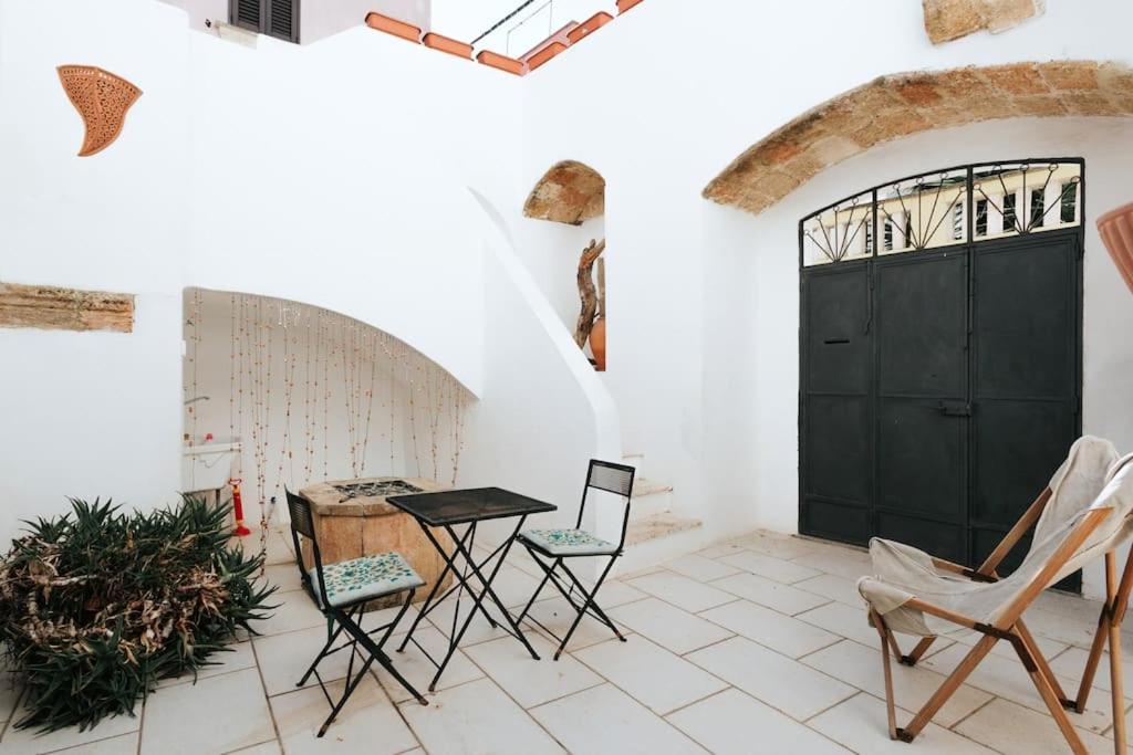 Zimmer mit einem Tisch und Stühlen sowie einer schwarzen Tür in der Unterkunft Nel Cuore del Salento, La Casa del Geco, Elegante Villa d’epoca in Ugento