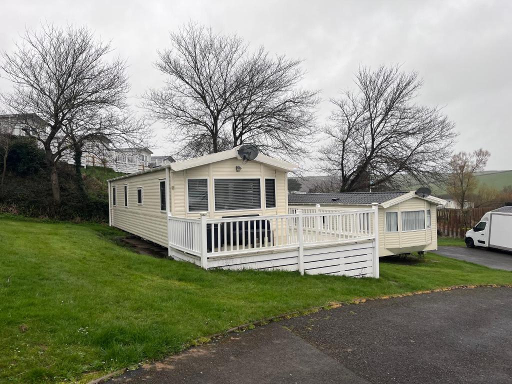a white mobile home with a porch on a yard at Take me to the beach at J&S caravan holidays Newquay Bay resort in Saint Columb Minor