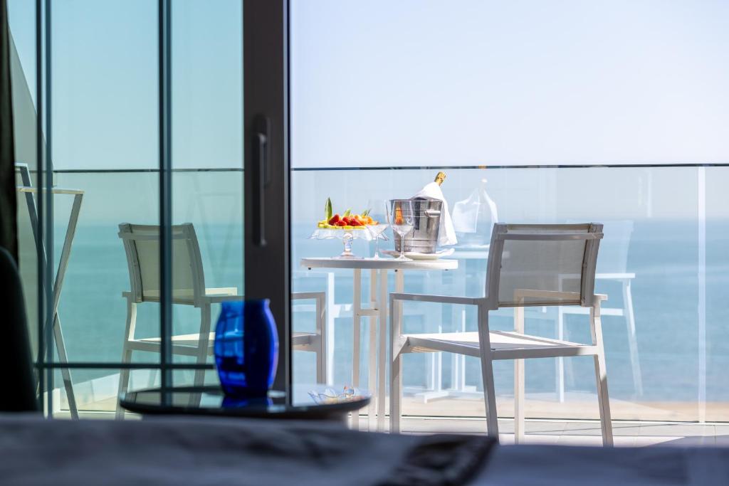 een eettafel met stoelen en een tafel met uitzicht op de oceaan bij Hotel Sporting in Rimini