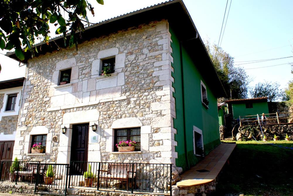 a green and white brick house with two windows at La Casa Verde del Sella in Mesariegos