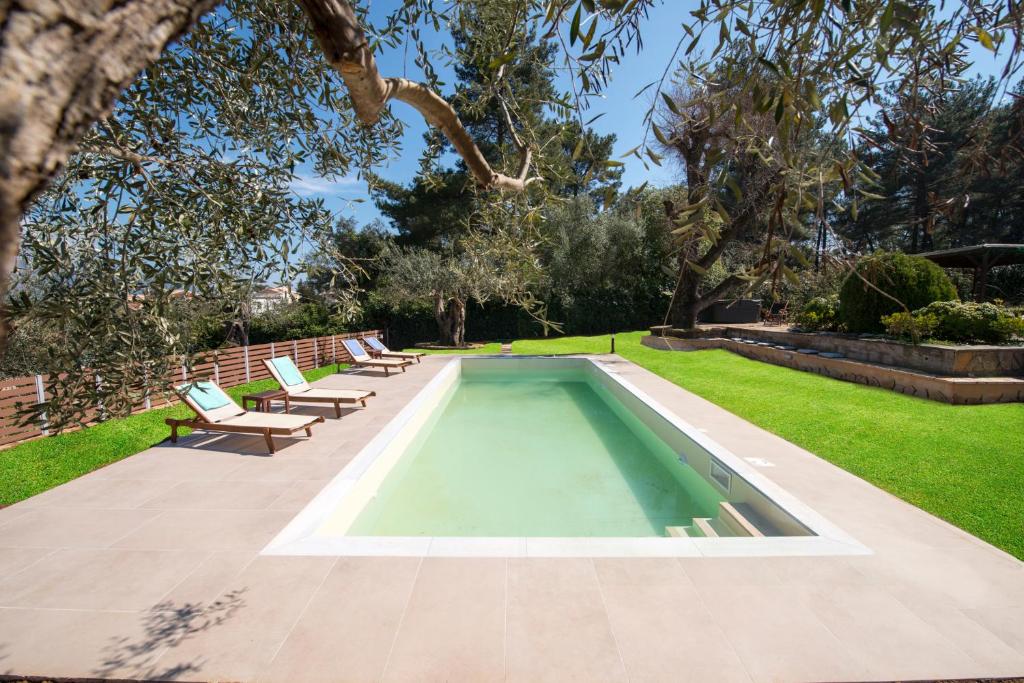 a swimming pool in the middle of a yard with benches at Spyrelia Villa with Private Pool & Outdoor Hot Tub in Dassia