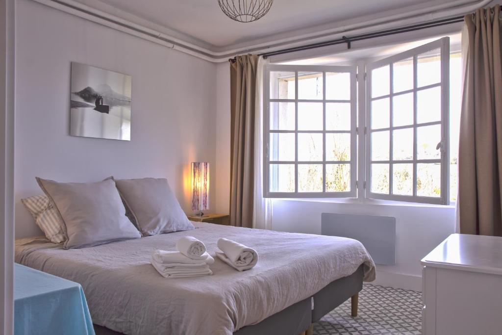 Un dormitorio blanco con una cama grande con toallas. en L'ORANGERIE 3* VUE IMPRENABLE, en Cambo-les-Bains