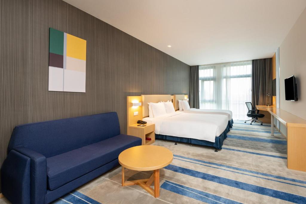 ein Hotelzimmer mit einem Bett und einem Sofa in der Unterkunft Holiday Inn Express Shanghai Pujiang, an IHG Hotel in Shanghai