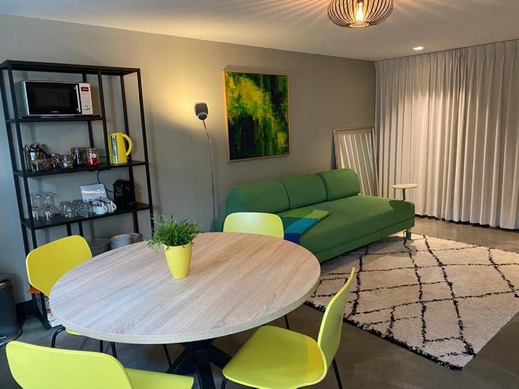 uma sala de estar com uma mesa e um sofá verde em Bed & breakfast 23 em Amerongen