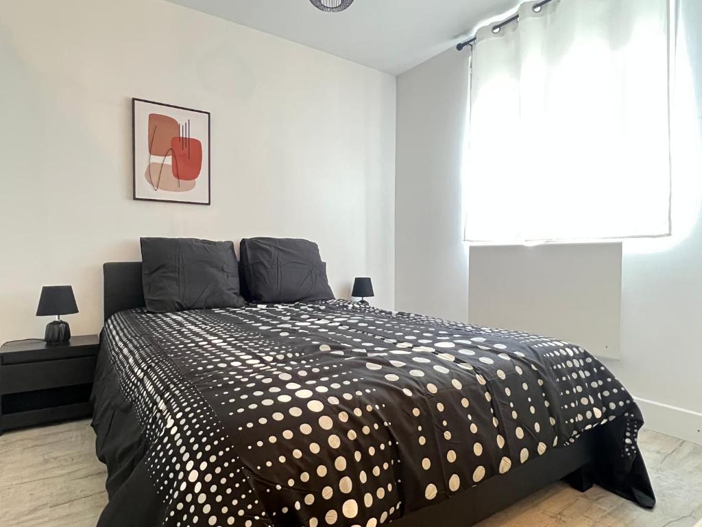 sypialnia z czarno-białym łóżkiem i oknem w obiekcie Maison de ville moderne proche du centre-ville w mieście Camon