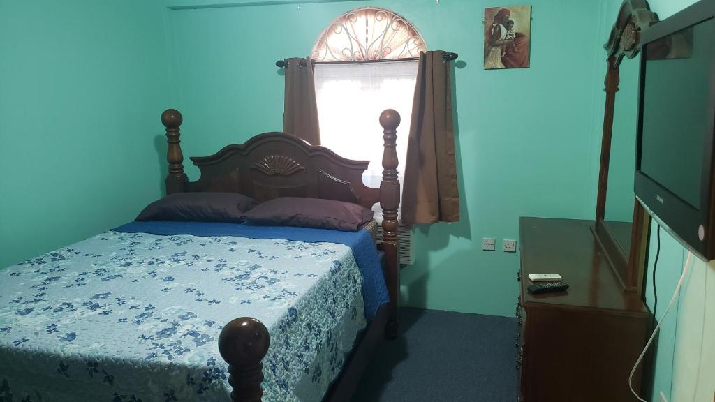 Elue's Inn في Mahaut: غرفة نوم زرقاء مع سرير ونافذة