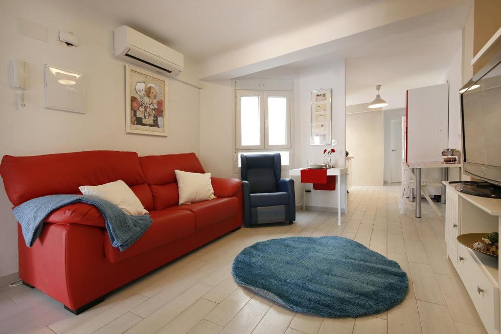 sala de estar con sofá rojo y alfombra azul en Apartment Capuchinos, en Málaga