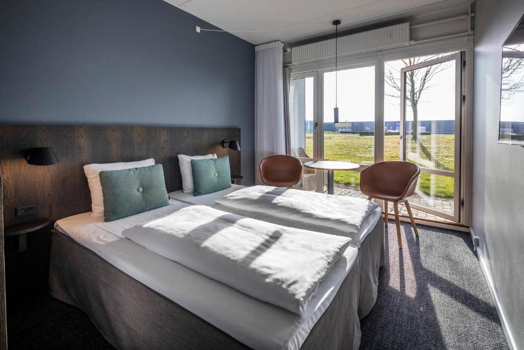 a bedroom with a large bed and a large window at Comwell Middelfart in Middelfart