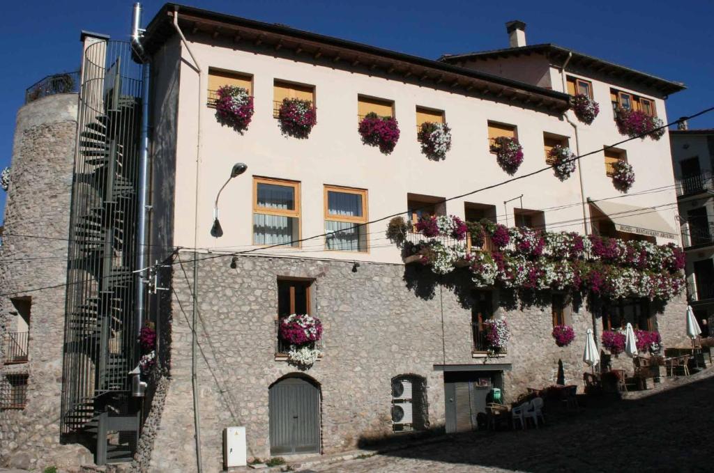 un bâtiment avec des boîtes de fleurs sur son côté dans l'établissement Hotel Arturo, à La Pobleta de Bellvei