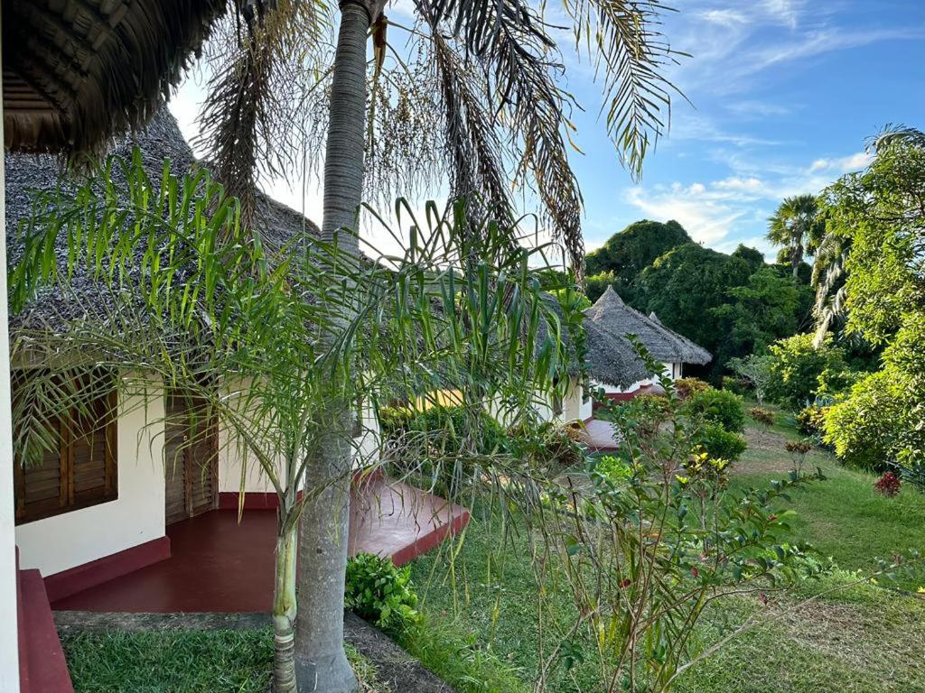 une maison avec un palmier en face dans l'établissement WINGS HOTELS, à Nosy Be