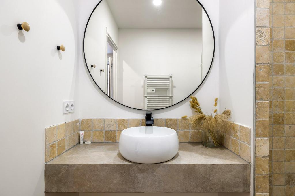La salle de bains est pourvue d'un miroir rond sur le mur. dans l'établissement MAYA Appartements & Suites, à Cosne Cours sur Loire