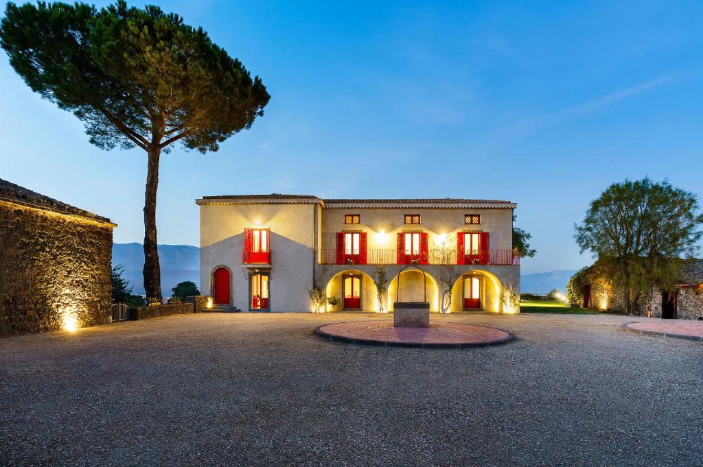 a large house with red doors and a tree at Etna Retreat in Castiglione di Sicilia