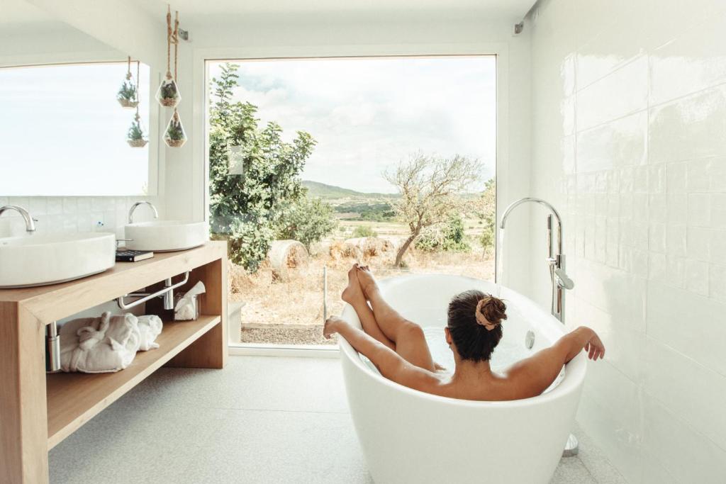 a woman laying in a bath tub in a bathroom at Cas Cabo Nou Agroturismo Adults Only in Sant Llorenç des Cardassar