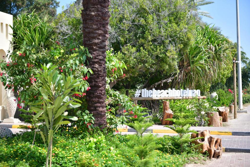 una palmera en un jardín con flores y plantas en Umm Al Quwain Beach Hotel, en Umm Al Quwain