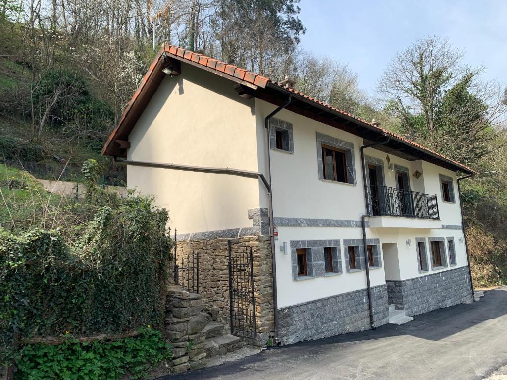 a white house with a balcony on top of it at Casa Rural en Santa Cruz-Mieres in Bustiello