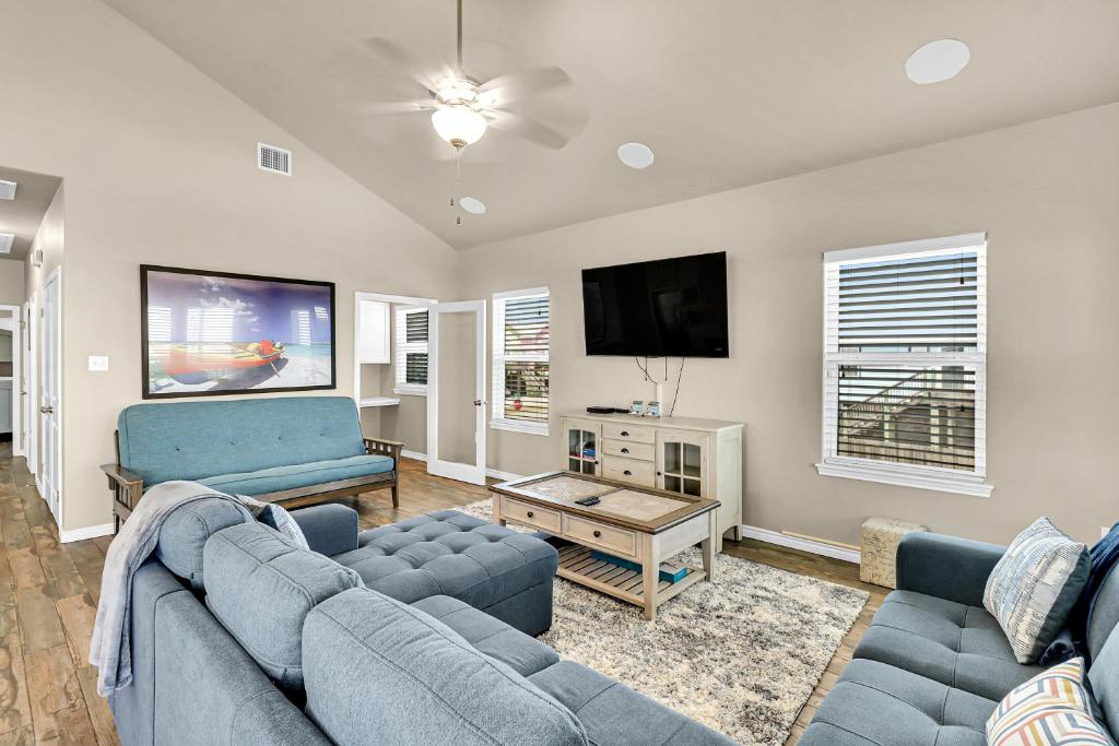 sala de estar con sofás azules y TV de pantalla plana en The Blue Pelican, en Corpus Christi