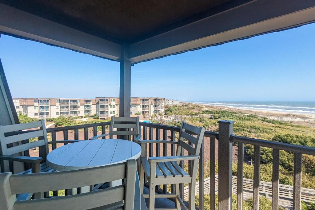 een balkon met een tafel en stoelen en het strand bij Southwinds F13 in Atlantic Beach