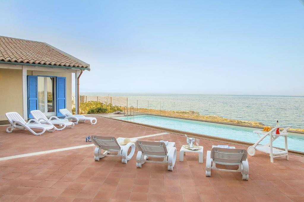 un patio avec des chaises et une piscine à côté de l'océan dans l'établissement Villa Ala, à Augusta