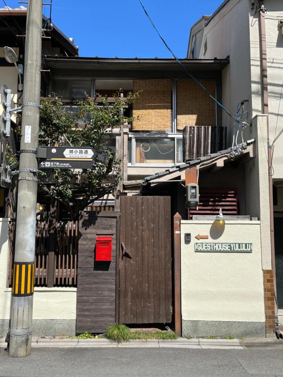 un edificio con una puerta de madera y una valla en Guesthouse Yululu, en Kioto