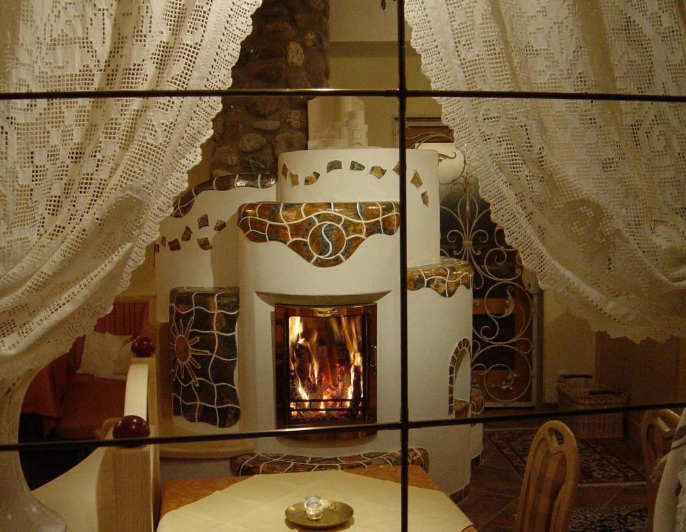 a table with a fireplace in a room with curtains at Pension & Appartement Steinwender in Bad Kleinkirchheim
