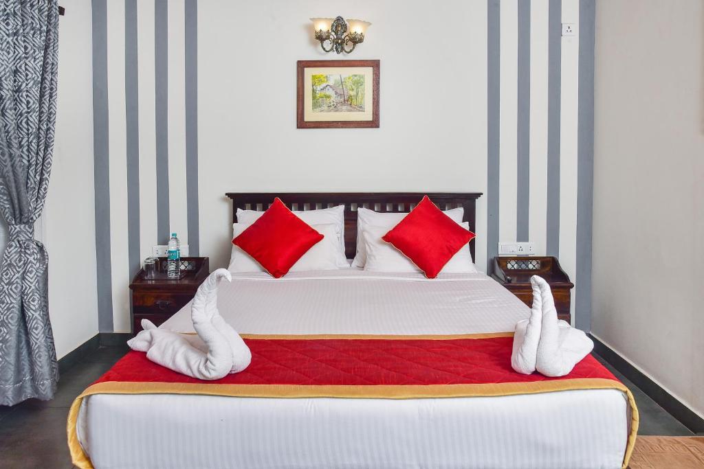 um quarto com uma cama grande e almofadas vermelhas e brancas em Clover Holiday Village em Madikeri