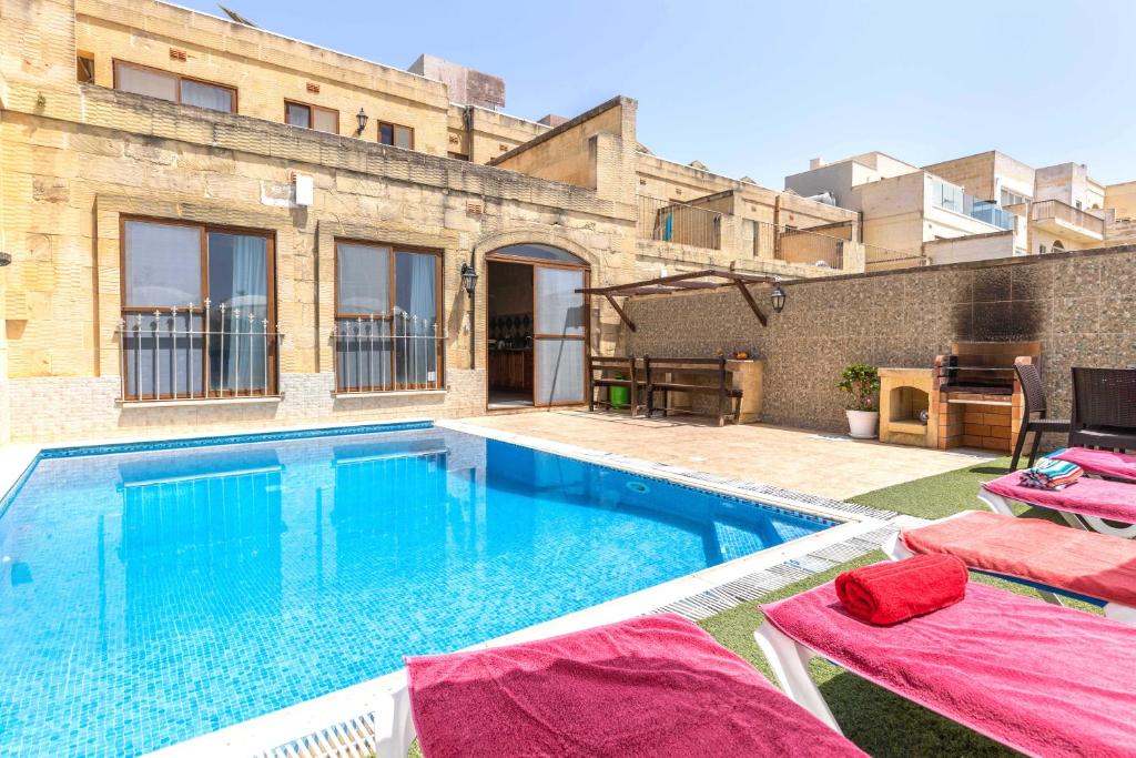 una piscina con due lettini accanto a un edificio di Ta Guljetta 4 bedroom Villa with private pool a Marsalforn