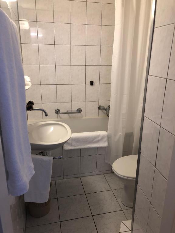 a bathroom with a sink and a toilet and a tub at Hotel Restaurant Heidihof in Maienfeld