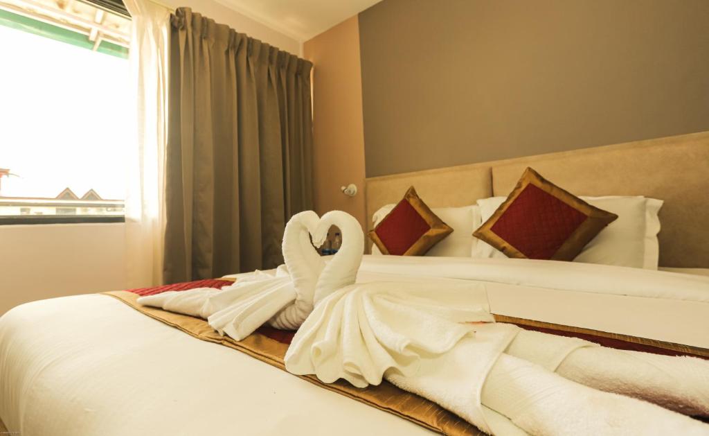 Hotel Buddha's Abode في دارامشالا: بجعة مصنوعة من المناشف جالسة على سرير