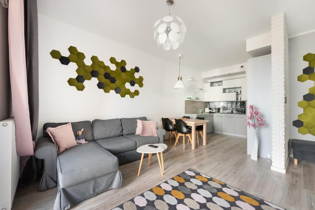 a living room with a gray couch and a kitchen at Ursynów Geometric Homey Apartment in Warsaw
