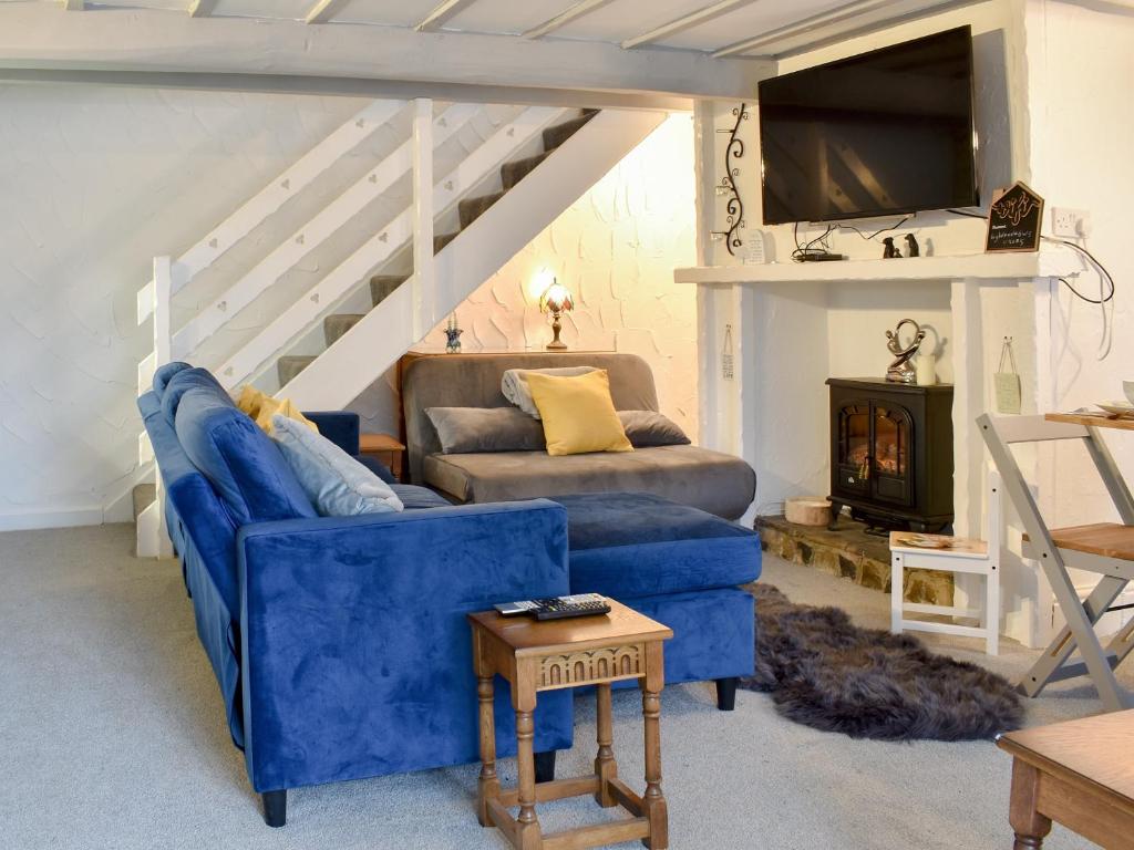 a living room with a blue couch and a tv at Weavers Cottage in Holmfirth