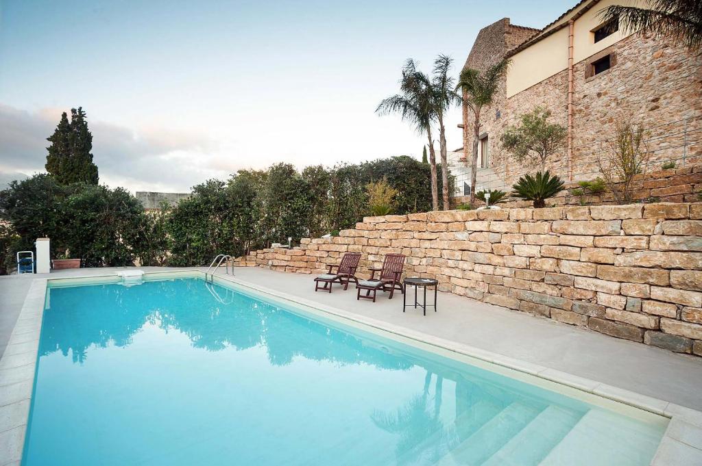 a swimming pool with two chairs next to a brick wall at Baglio Maranzano - Titi in Buseto Palizzolo