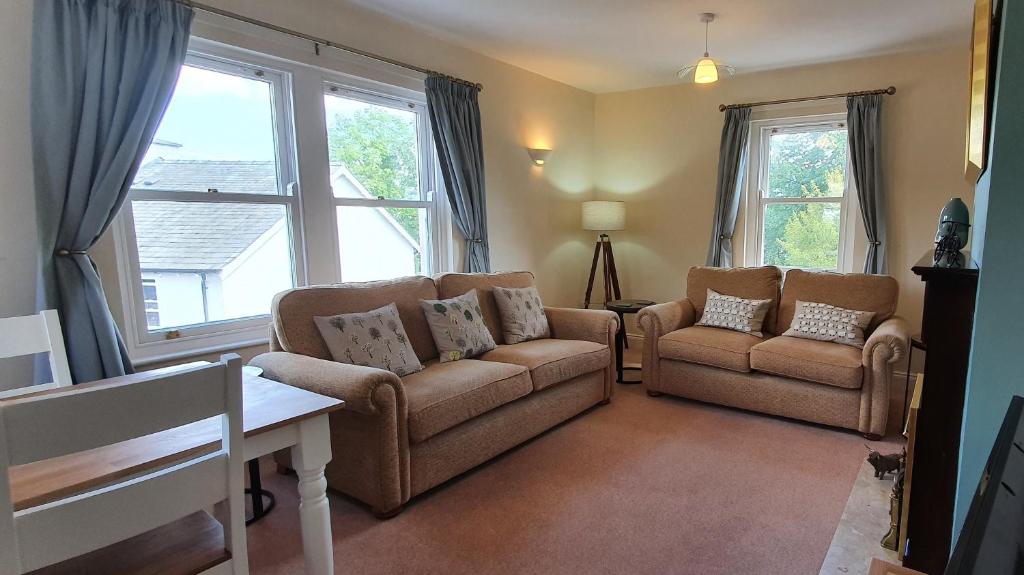 a living room with a couch and chairs and windows at Skiddaw. 20 Greta Grove House in Keswick