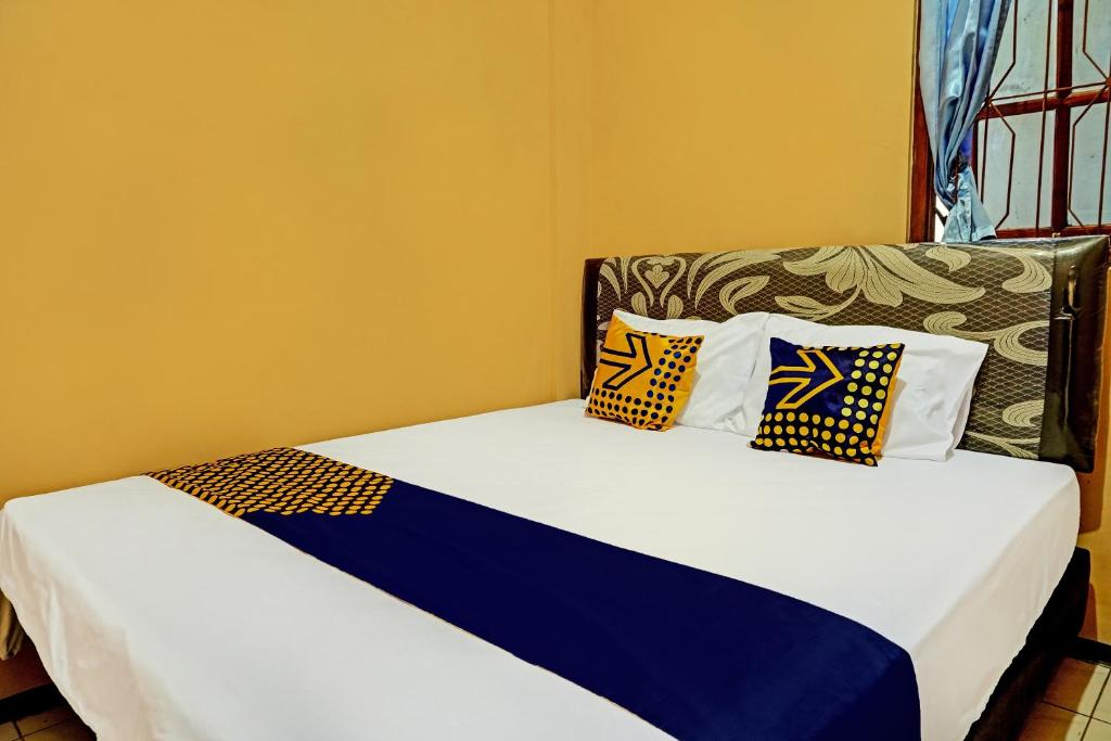 a bed with two pillows on it in a room at SPOT ON 92450 Homestay Simpang Panji Suroso Syariah in Malang
